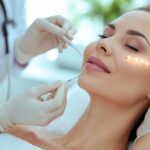 A woman receiving a non-surgical facial rejuvenation treatment from a beautician in a modern clinic.